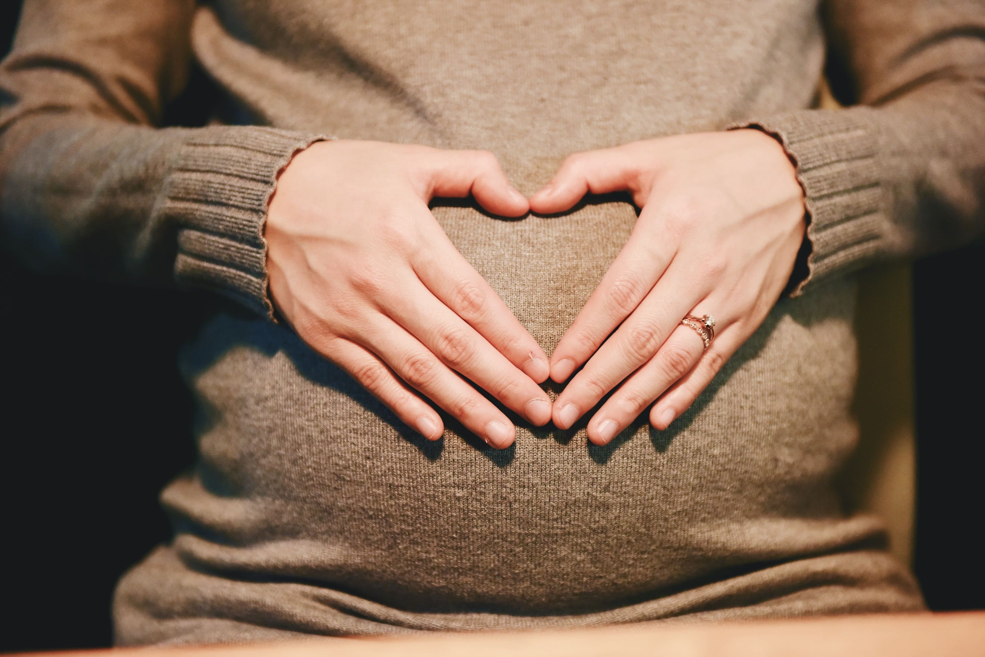 Pregnant woman holding her belly with a heart
