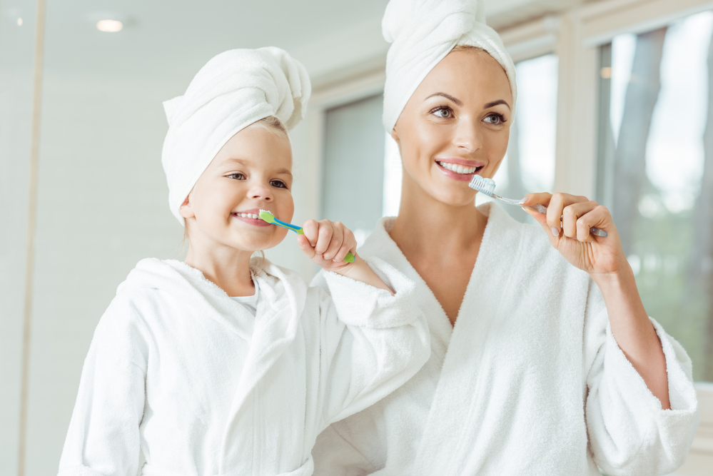 Mother and daughter brushing teeth together