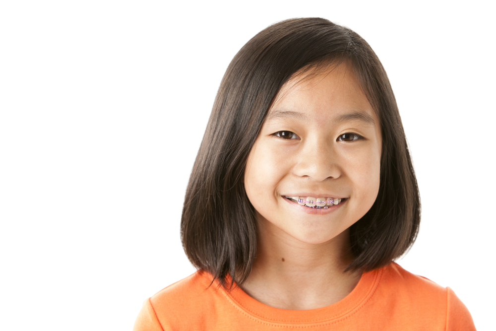 Young child smiling and wearing braces