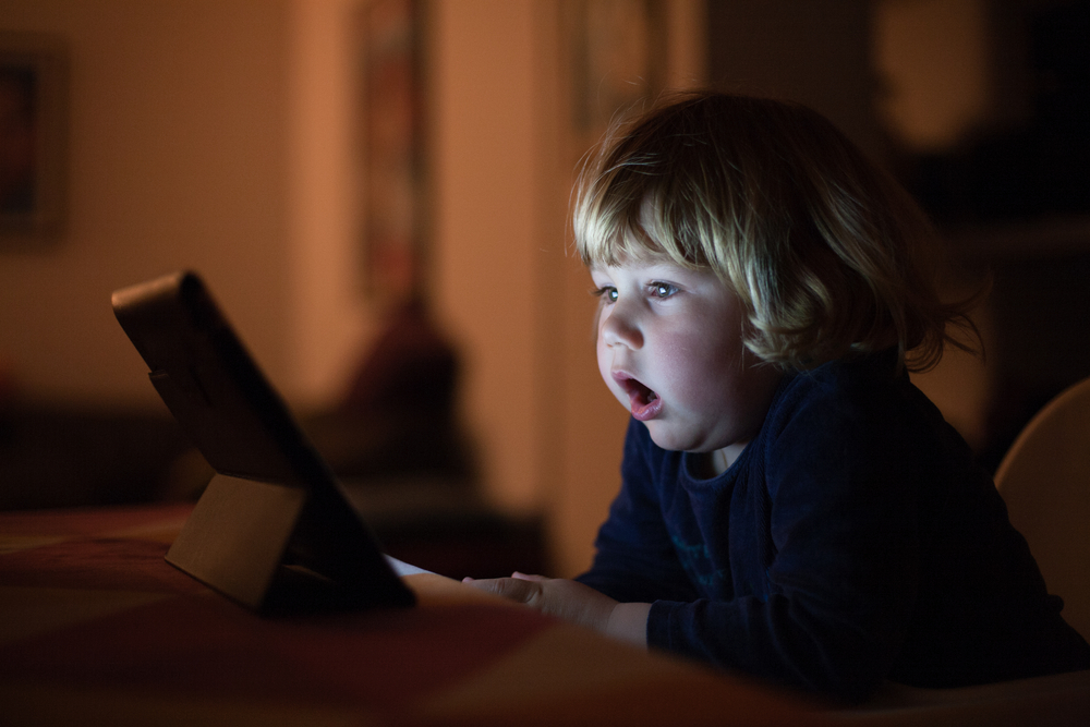 a child watching a tablet with their mouth open for breathing