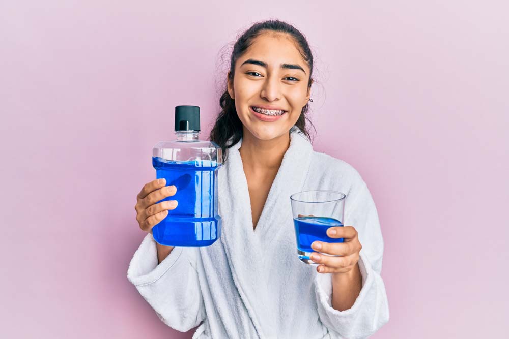 a girl with braces holding a bottle of mouthwash