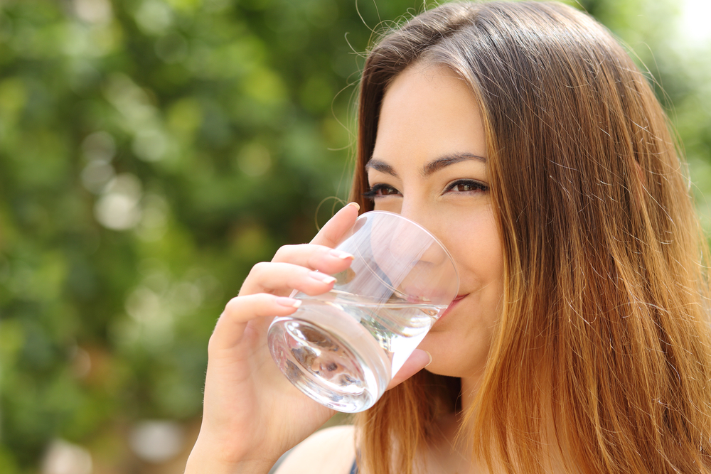 a woman outside drinking tap water from a glass