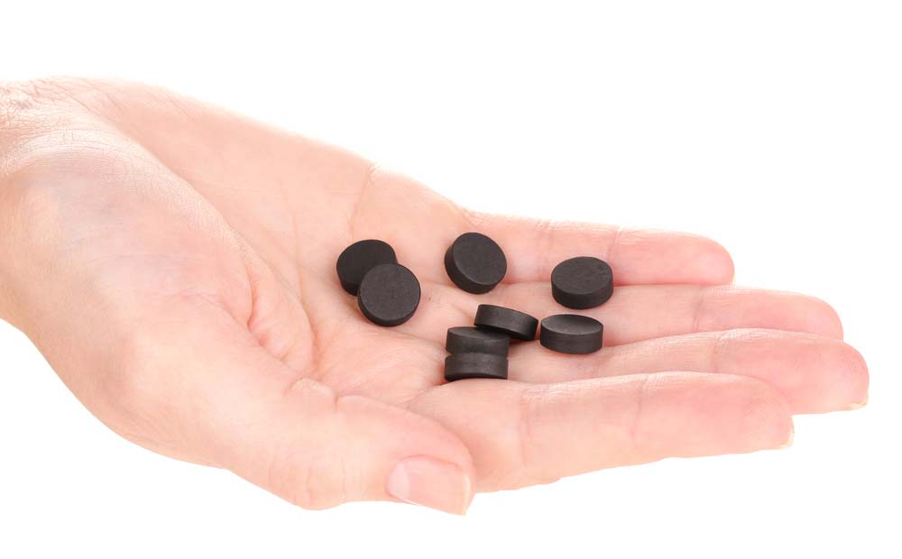 activated charcoal in tablets on a person’s hand
