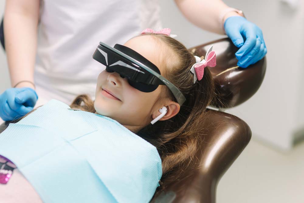 A girl wears a VR headset and headphones while in the dentist’s chair.
